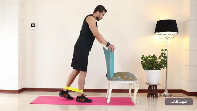 آموزش حرکت ورزشی پشت پا ایستاده زانوی خم با کش (دست تکیه گاه)