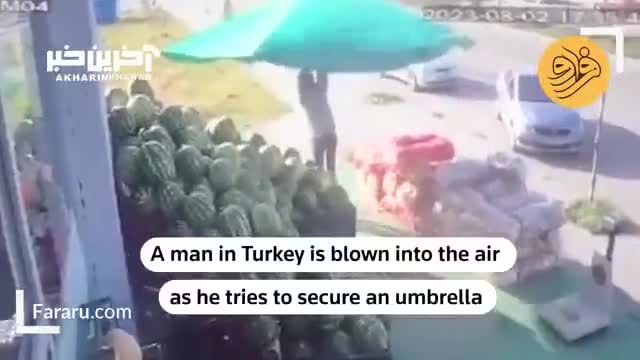 باد شدید مردی با چترش را به هوا برد!