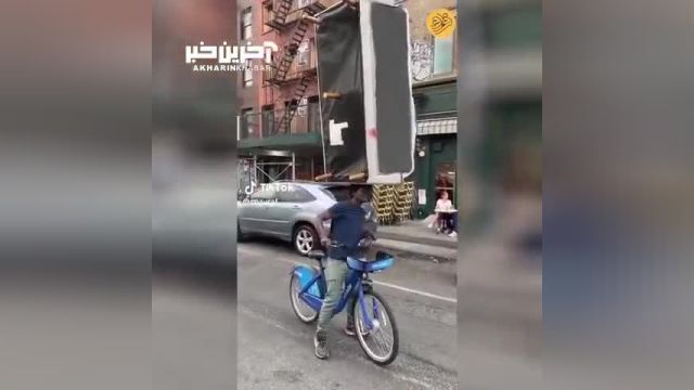 دوچرخه سواری که روی سرش مبل حمل می‌کند!