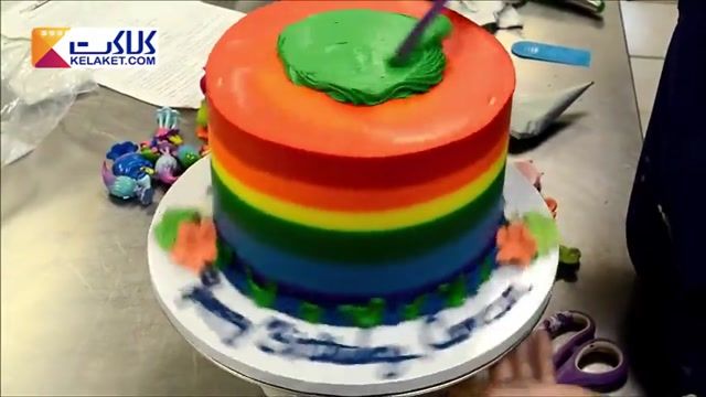 تزیین کیک با لایه های رنگی رنگی بهمراه گل و آدم که با خمیر فوندانت ساخته شده اند